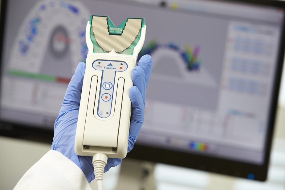 Dentist holding a Tekscan T-Scan sensor with bite force analysis on screen